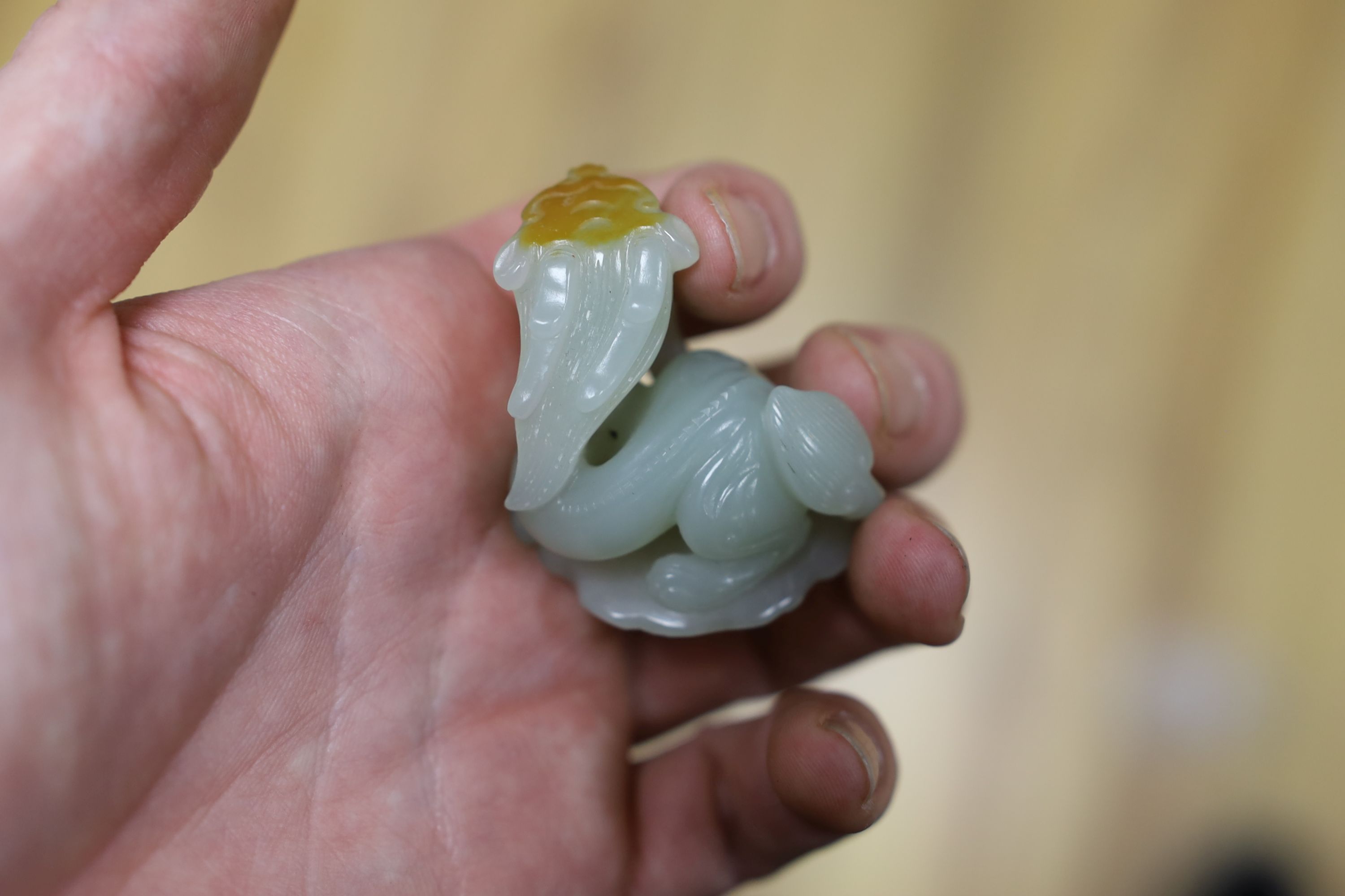 A Chinese pale celadon and russet skin jade figure of a dragon, 4cm high